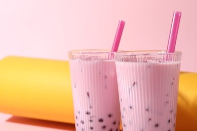 Photo of Tasty milk bubble tea in glasses on color background, closeup. Space for text