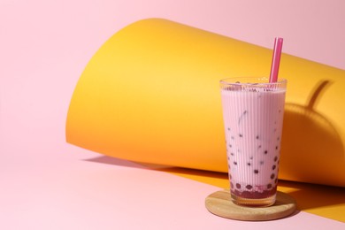 Photo of Tasty milk bubble tea in glass on color background, space for text