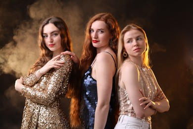 Photo of Beautiful women with different hair colors on dark background with smoke