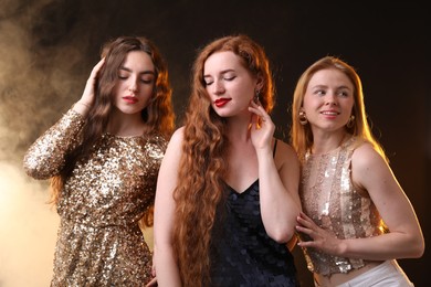 Photo of Beautiful women with different hair colors on dark background with smoke
