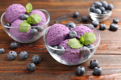 Photo of Tasty sorbet with blueberries and mint served on wooden table, closeup