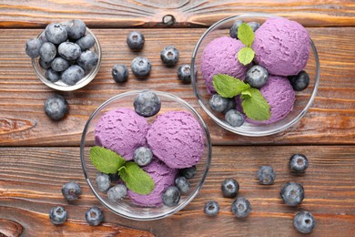 Photo of Tasty sorbet with blueberries and mint served on wooden table, flat lay
