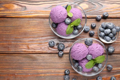 Photo of Tasty sorbet with blueberries and mint served on wooden table, flat lay. Space for text