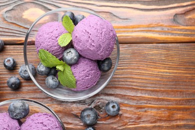 Photo of Tasty sorbet with blueberries and mint served on wooden table, flat lay. Space for text