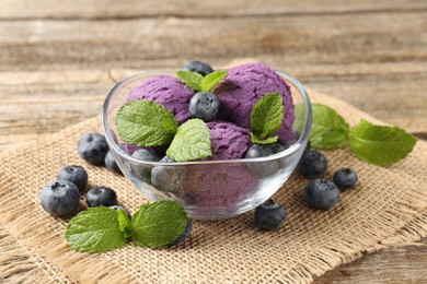 Photo of Tasty sorbet with blueberries and mint served on wooden table, closeup