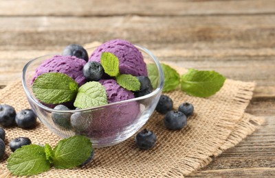 Photo of Tasty sorbet with blueberries and mint served on wooden table, closeup. Space for text