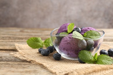 Photo of Tasty sorbet with blueberries and mint served on wooden table, closeup. Space for text