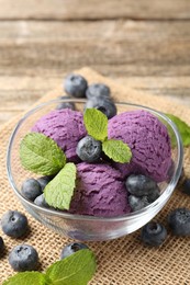 Photo of Tasty sorbet with blueberries and mint served on wooden table, closeup