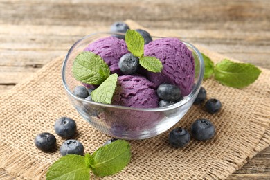 Photo of Tasty sorbet with blueberries and mint served on wooden table, closeup