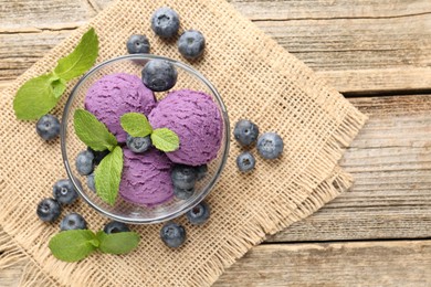 Photo of Tasty sorbet with blueberries and mint served on wooden table, flat lay. Space for text