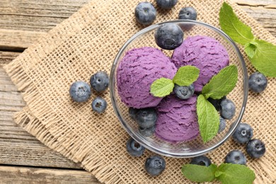Photo of Tasty sorbet with blueberries and mint served on wooden table, flat lay. Space for text