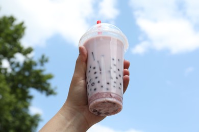 Photo of Woman with tasty milk bubble tea in plastic cup outdoors, closeup