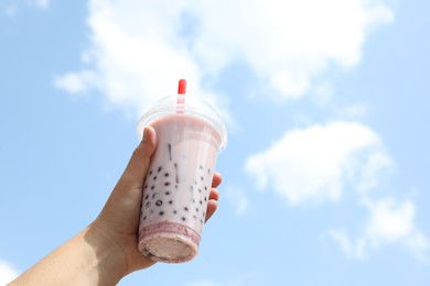 Photo of Woman with tasty milk bubble tea in plastic cup outdoors, closeup. Space for text