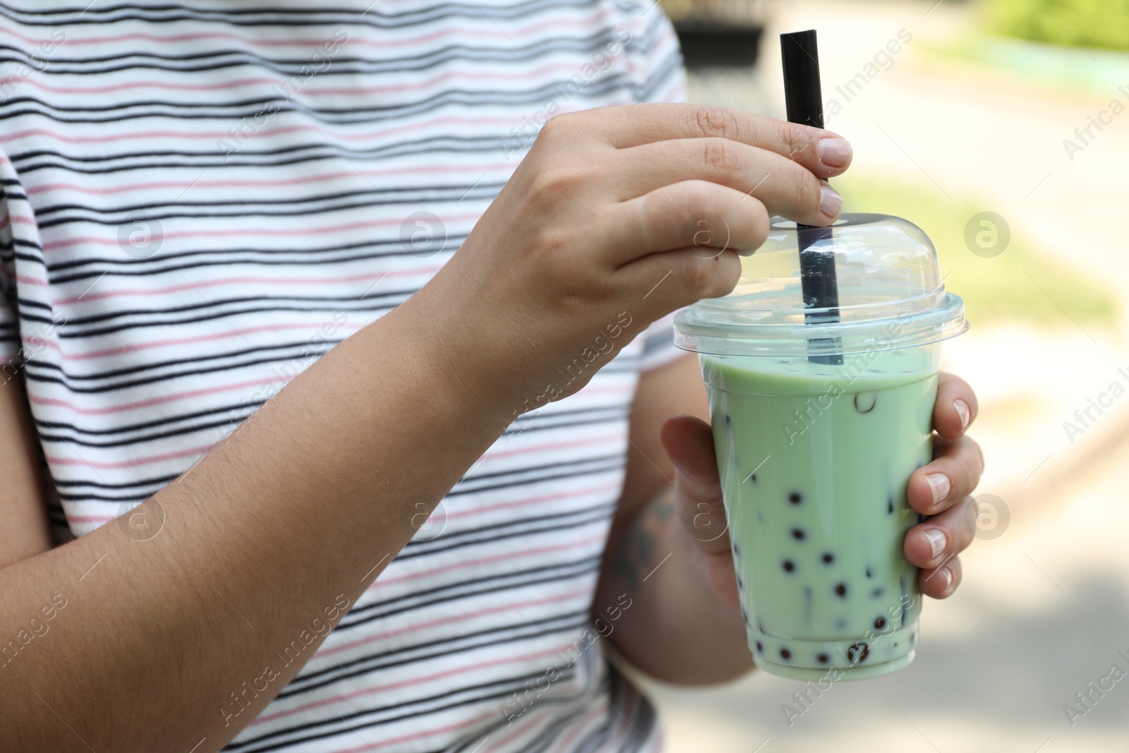 Woman with tasty milk bubble tea in plastic cup outdoors, closeup Photo of Woman with tasty milk bubble tea in plastic cup outdoors, closeup