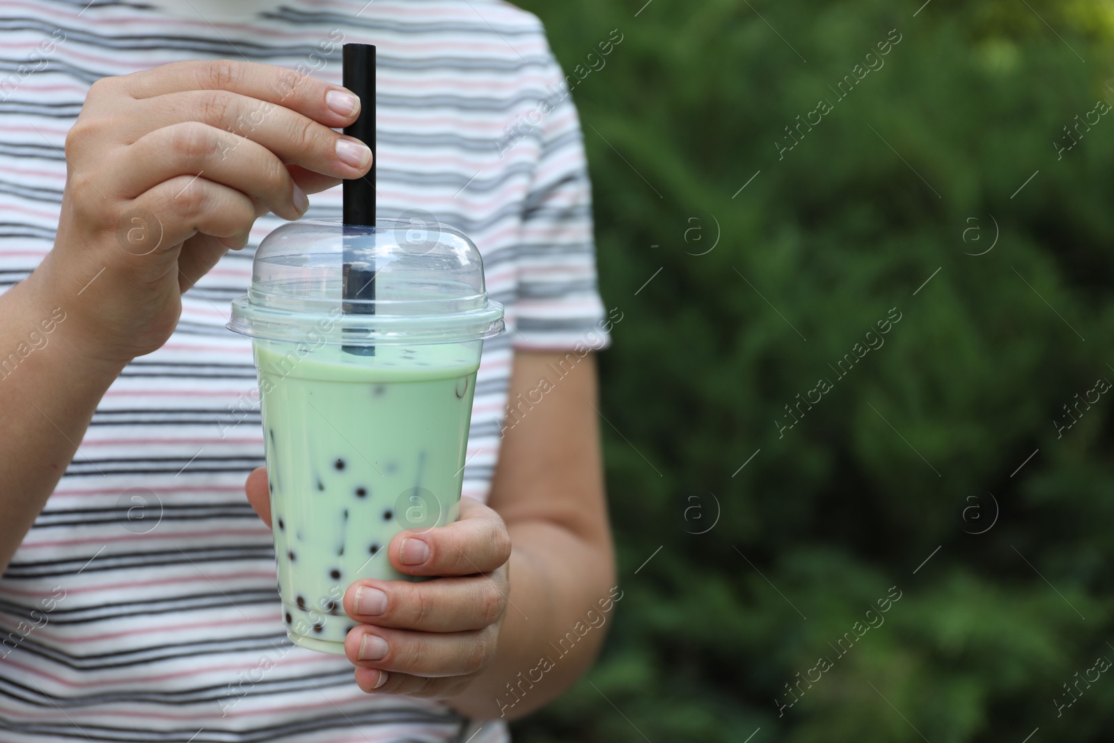 Woman with tasty milk bubble tea in plastic cup outdoors, closeup. Space for text Photo of Woman with tasty milk bubble tea in plastic cup outdoors, closeup. Space for text