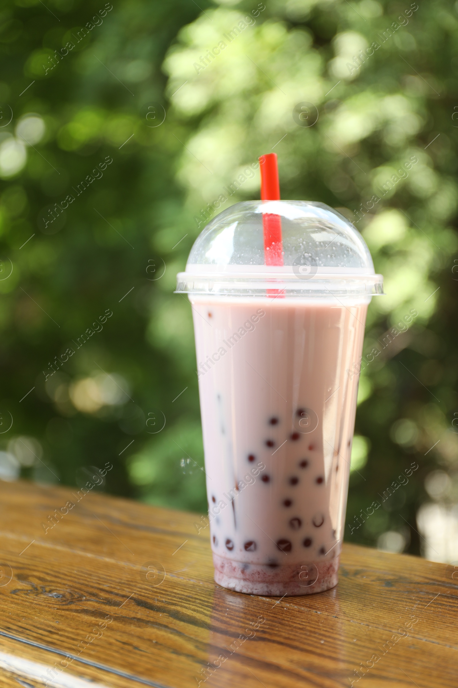 Tasty milk bubble tea in plastic cup on wooden table Photo of Tasty milk bubble tea in plastic cup on wooden table