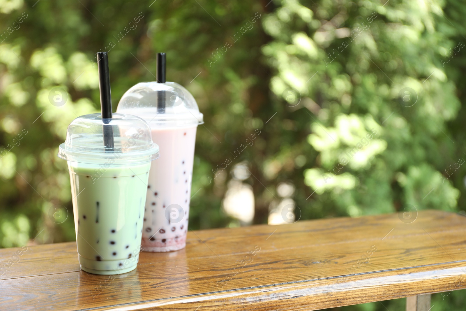 Tasty milk bubble tea in plastic cups on wooden table. Space for text Photo of Tasty milk bubble tea in plastic cups on wooden table. Space for text