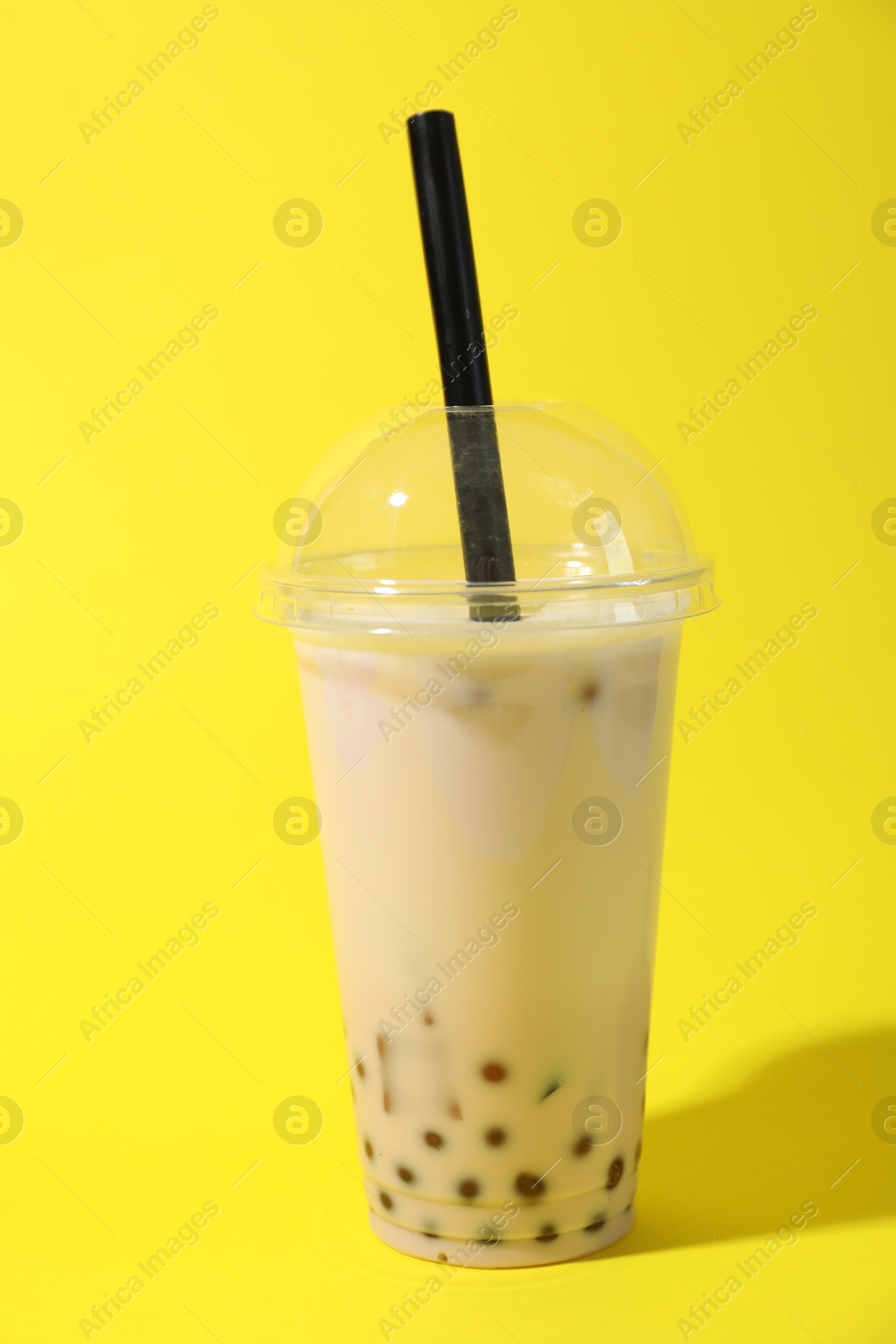 Tasty milk bubble tea in plastic cup on yellow background Photo of Tasty milk bubble tea in plastic cup on yellow background