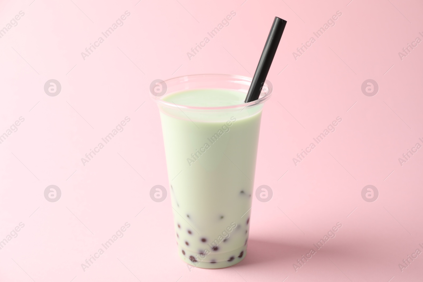 Tasty milk bubble tea in plastic cup on pink background Photo of Tasty milk bubble tea in plastic cup on pink background