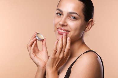 Photo of Young woman with lip balm on beige background