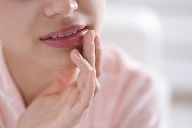 Photo of Young woman with lip balm at home, closeup. Space for text