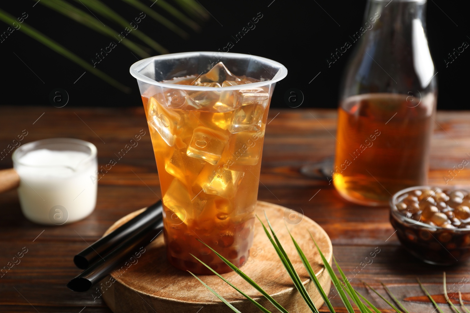 Tasty iced bubble tea and ingredients on wooden table Photo of Tasty iced bubble tea and ingredients on wooden table