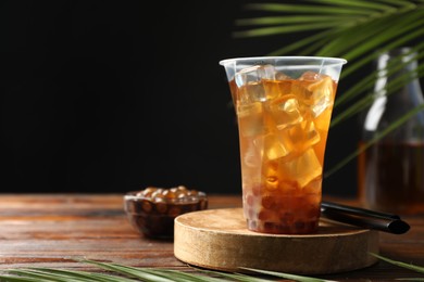 Photo of Tasty iced bubble tea and ingredients on wooden table. Space for text