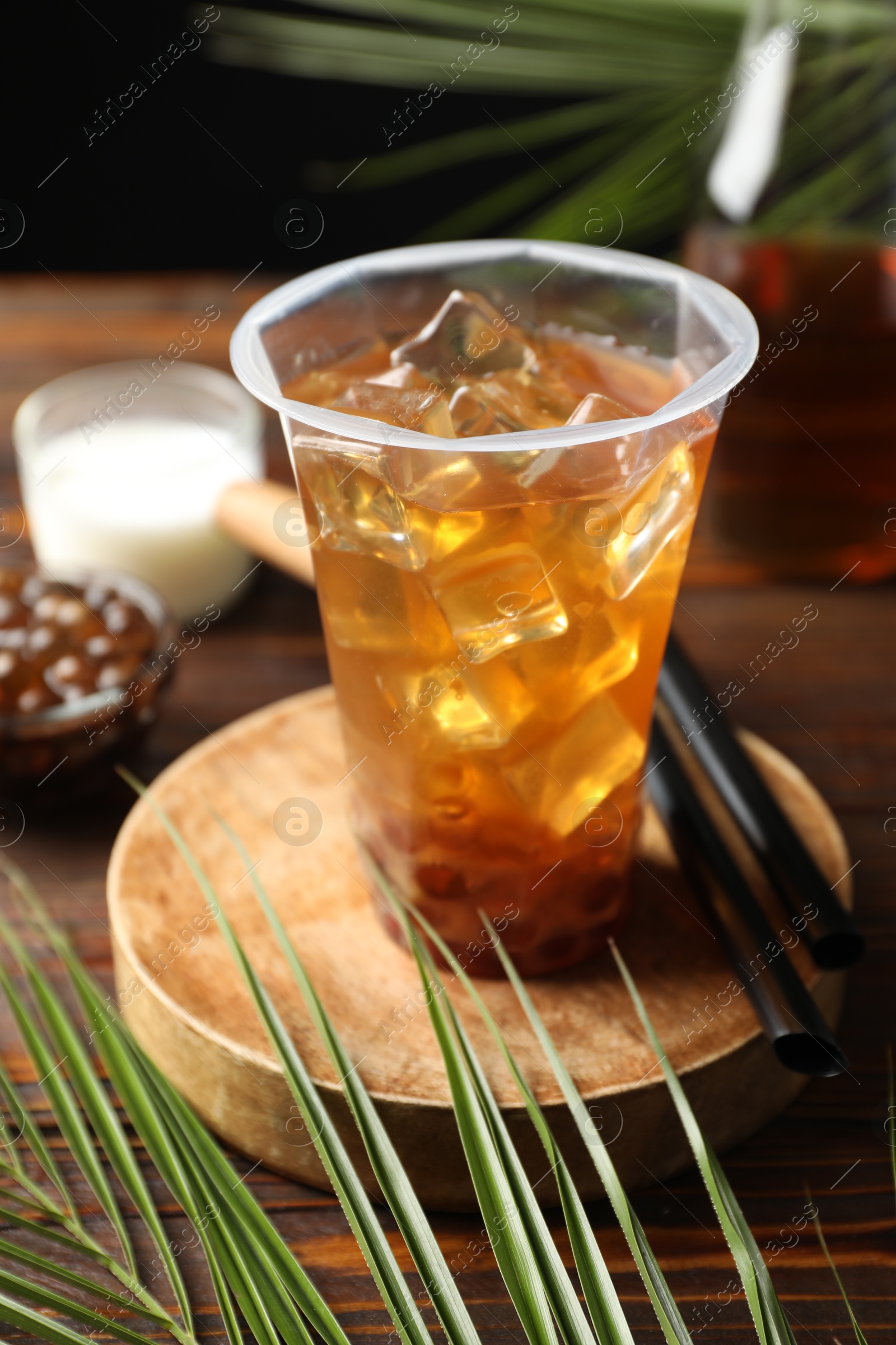 Tasty iced bubble tea and ingredients on wooden table Photo of Tasty iced bubble tea and ingredients on wooden table