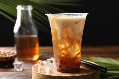 Photo of Tasty iced bubble tea and ingredients on wooden table, closeup