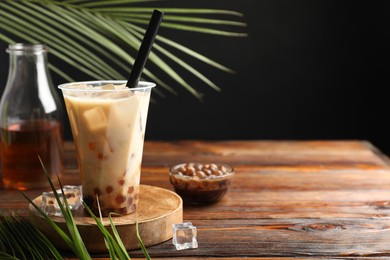 Photo of Tasty iced bubble tea and ingredients on wooden table. Space for text