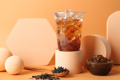 Photo of Tasty iced bubble tea and ingredients on orange background