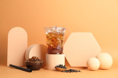 Photo of Tasty iced bubble tea and ingredients on orange background