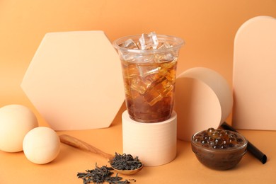 Photo of Tasty iced bubble tea and ingredients on orange background