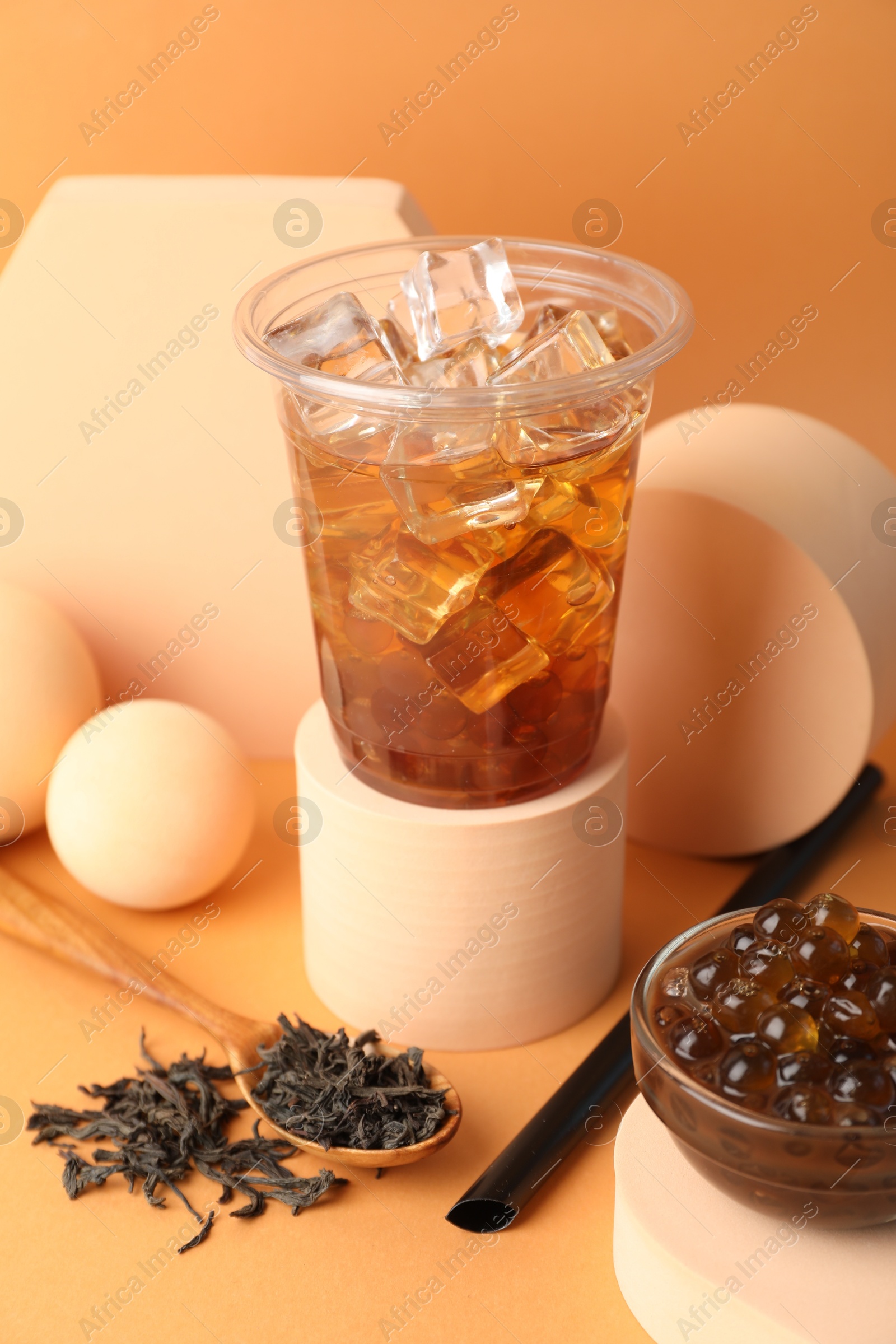 Tasty iced bubble tea and ingredients on orange background Photo of Tasty iced bubble tea and ingredients on orange background