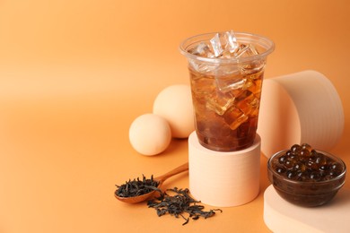 Photo of Tasty iced bubble tea and ingredients on orange background. Space for text