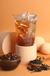 Photo of Tasty iced bubble tea and ingredients on orange background