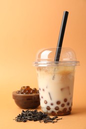 Photo of Tasty iced bubble tea and ingredients on orange background