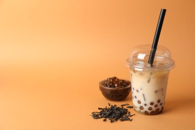 Photo of Tasty iced bubble tea and ingredients on orange background. Space for text