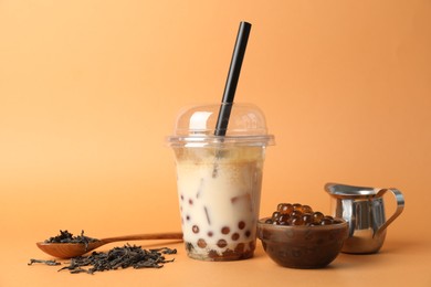 Photo of Tasty iced bubble tea and ingredients on orange background