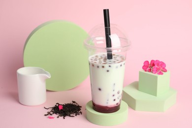 Photo of Tasty refreshing bubble tea and flower on pink background