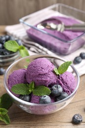 Photo of Tasty sorbet with blueberries and mint on wooden table, closeup