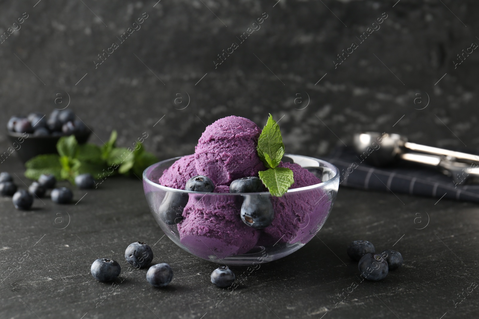 Photo of Tasty sorbet with blueberries and mint on black table, closeup