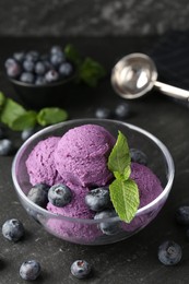 Photo of Tasty sorbet with blueberries and mint on black table, closeup