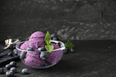 Photo of Tasty sorbet with blueberries and mint on black table, closeup. Space for text
