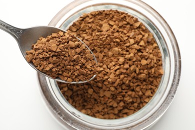Photo of Spoon with instant coffee over bowl against white background, top view