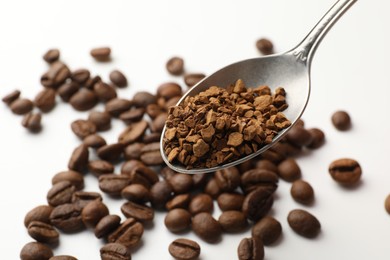 Photo of Spoon with instant coffee and beans on white table, closeup