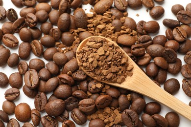 Photo of Spoon with instant coffee and beans on white table, closeup