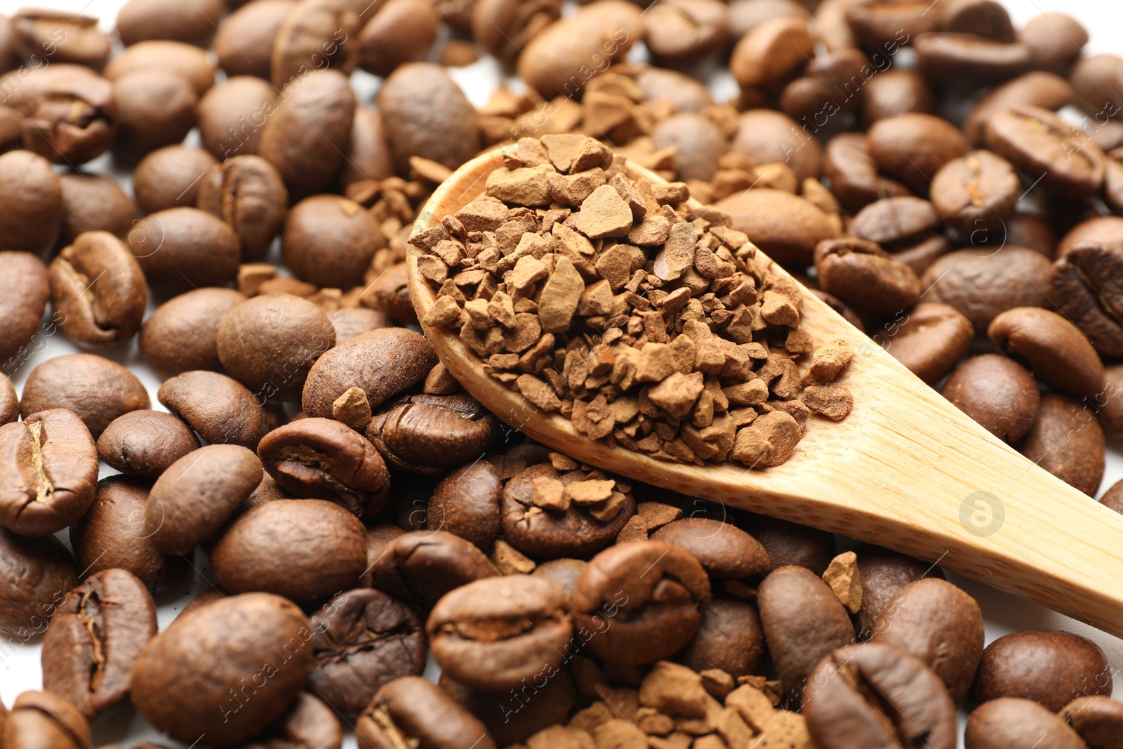Spoon with instant coffee and beans on white table, closeup Photo of Spoon with instant coffee and beans on white table, closeup