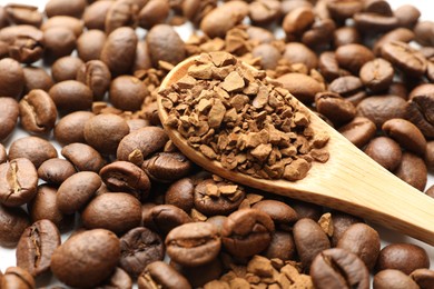 Photo of Spoon with instant coffee and beans on white table, closeup
