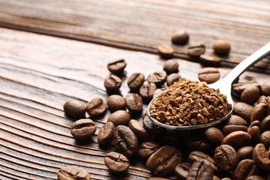 Photo of Spoon with instant coffee and beans on wooden table, closeup. Space for text